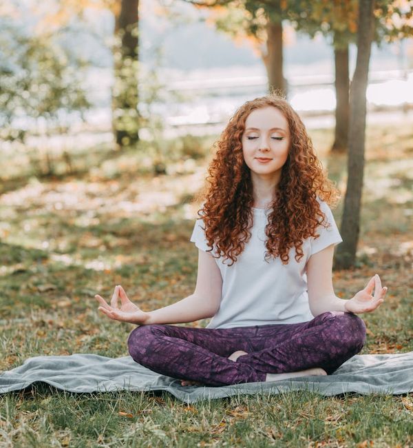 Person meditating peacefully in a calm natural setting.